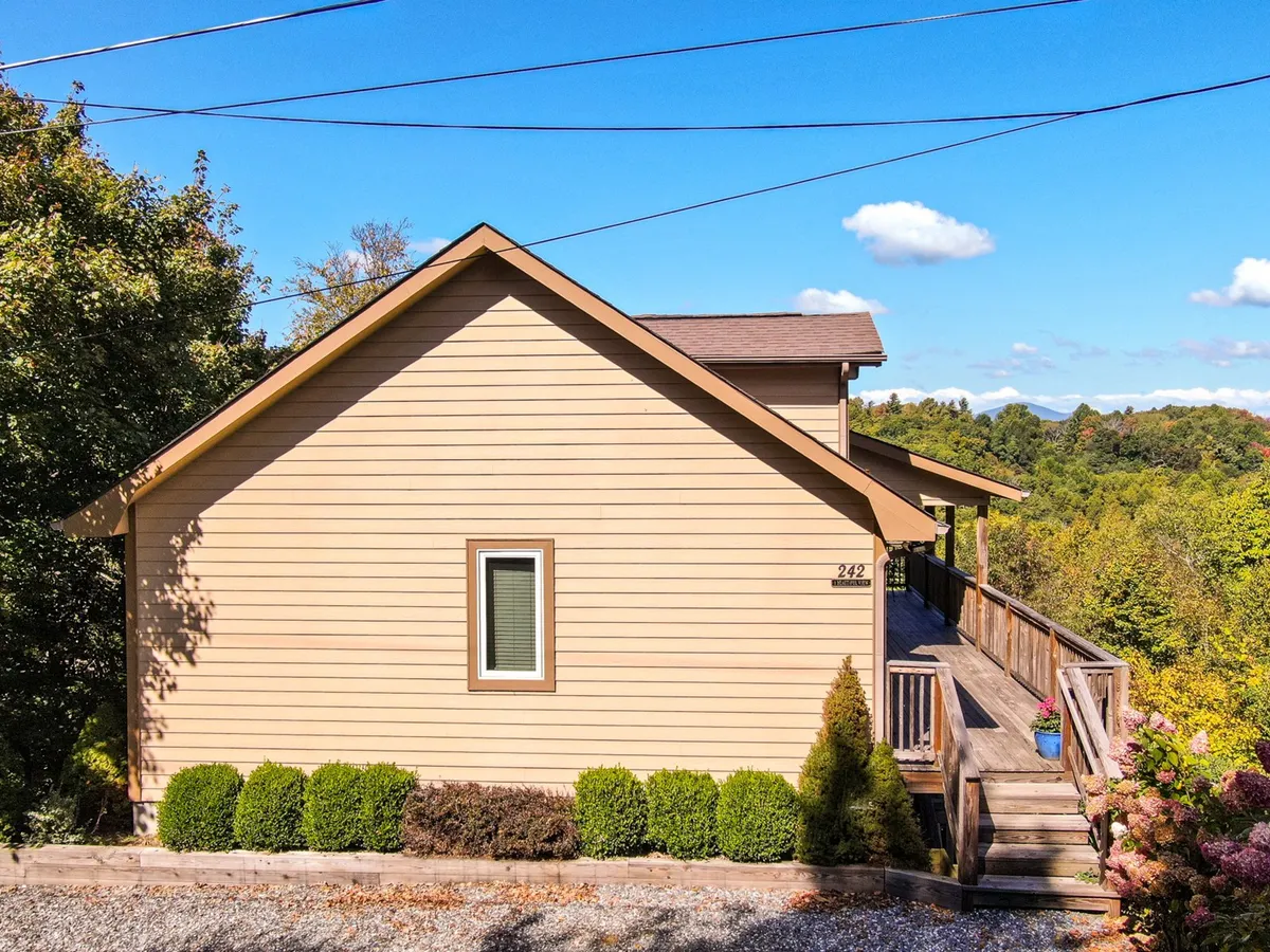 The house's welcoming facade features a spacious deck and landscaped garden. The setting conveys a sense of arrival and outdoor gathering space, hinting at family get-togethers and the convenience of nearby homes for larger groups.