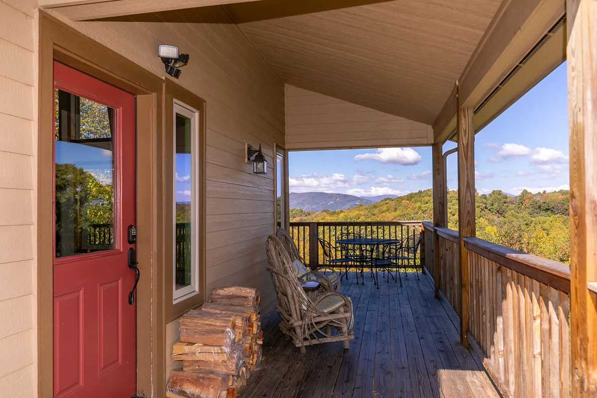 A peaceful wooden deck with a red door and rocking chair offers a direct view of the mountains, inviting relaxation and contemplation of the surrounding landscape. Seasonal elements like mountain sunrises can enhance the winter experience here.